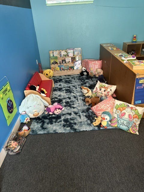 Classroom reading nook with a small sofa, rug, pillows, and bookshelf