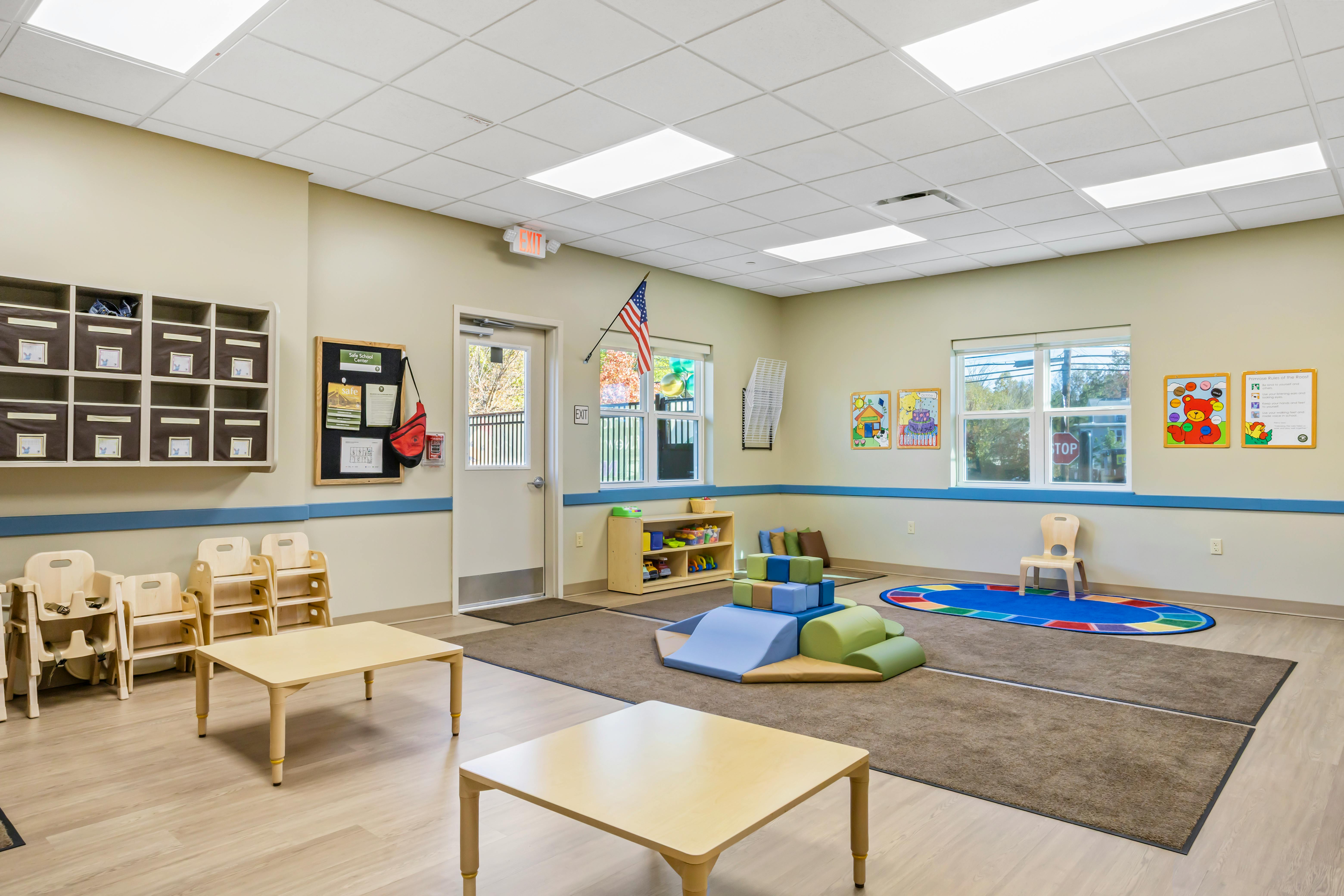 Empty early childhood classroom with small tables, chairs, and play equipment
