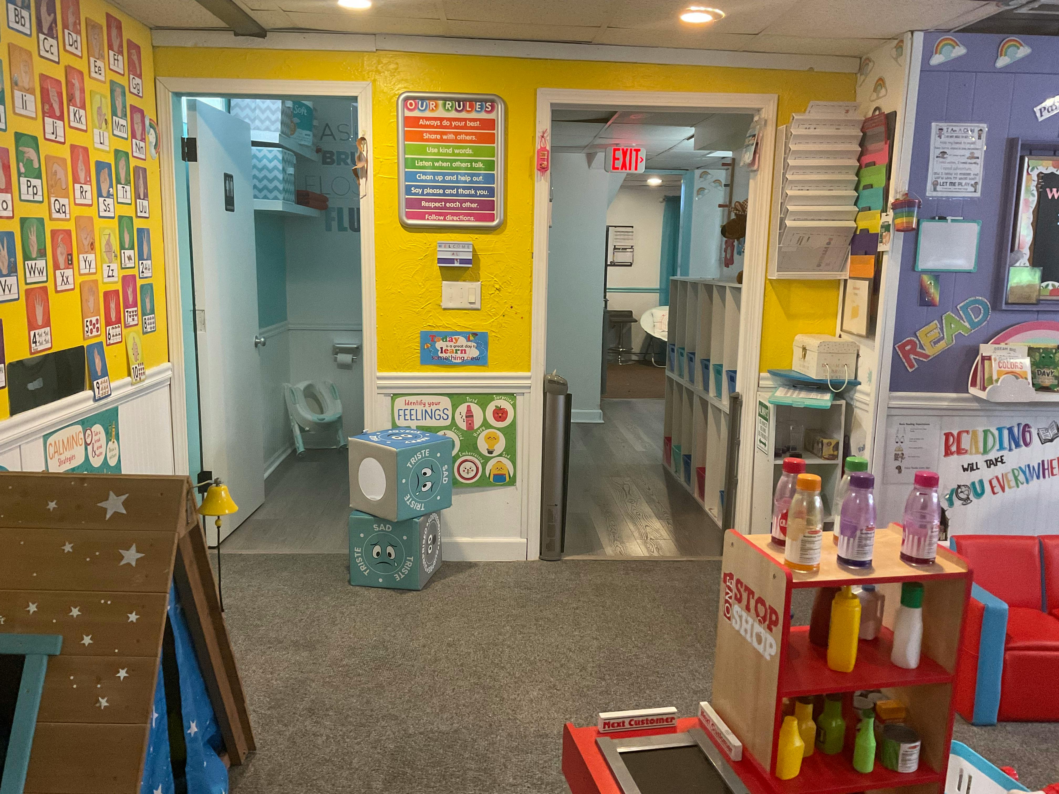 Classroom with yellow walls, open doors to a bathroom and another room