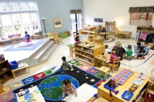Children playing in a classroom with various toys and activity stations