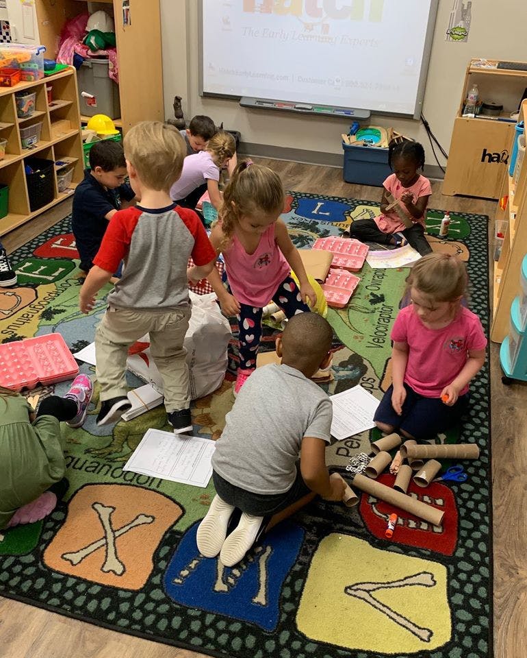 Children playing on a rug with various items
