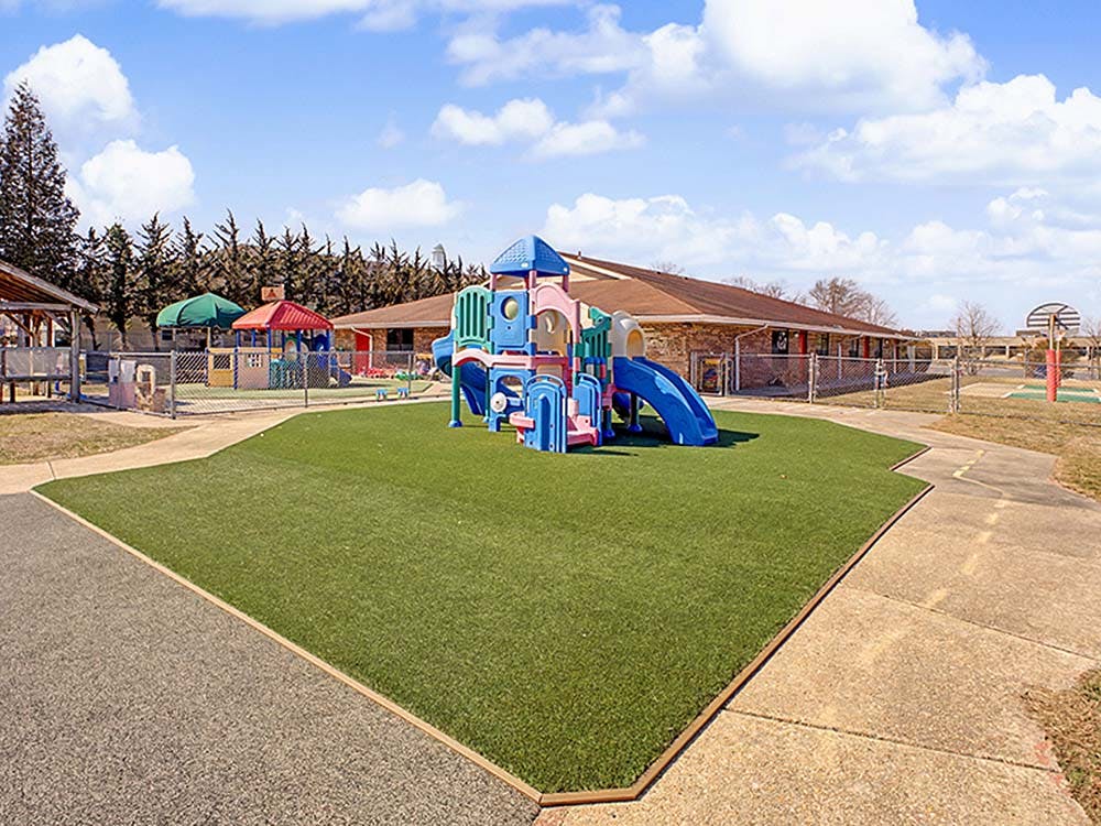 Colorful playground structure on artificial turf with building in background