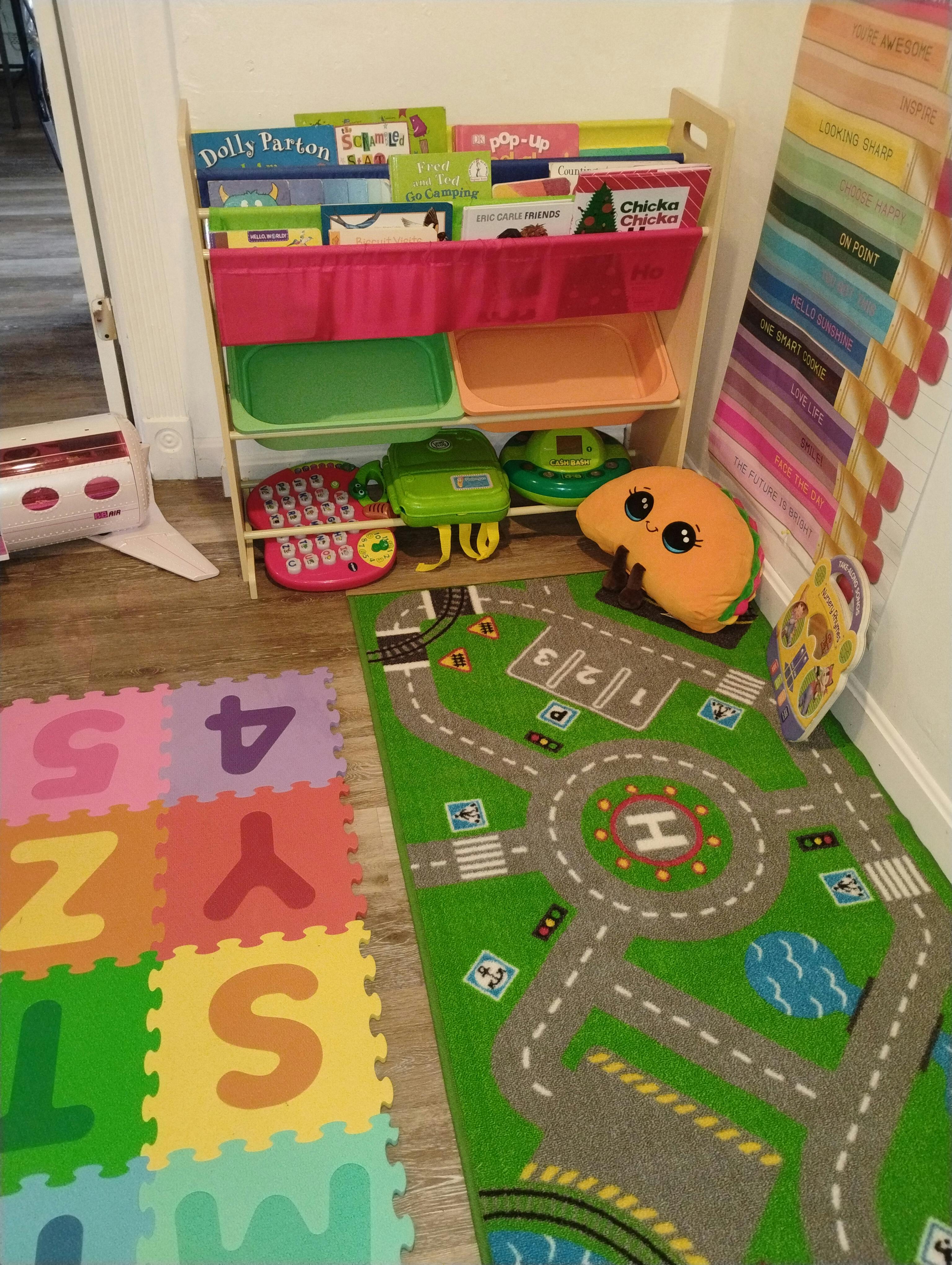 Playroom with a shelf of children's books, toys, play mat with numbers and letters