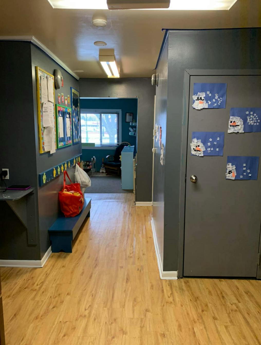 Hallway with bulletin boards, a bench, and a door with decorations