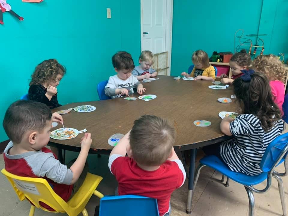 Children and an adult seated around a table doing an activity