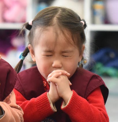 Child with closed eyes and hands clasped