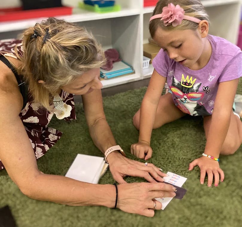 Adult and child on floor looking at small cards