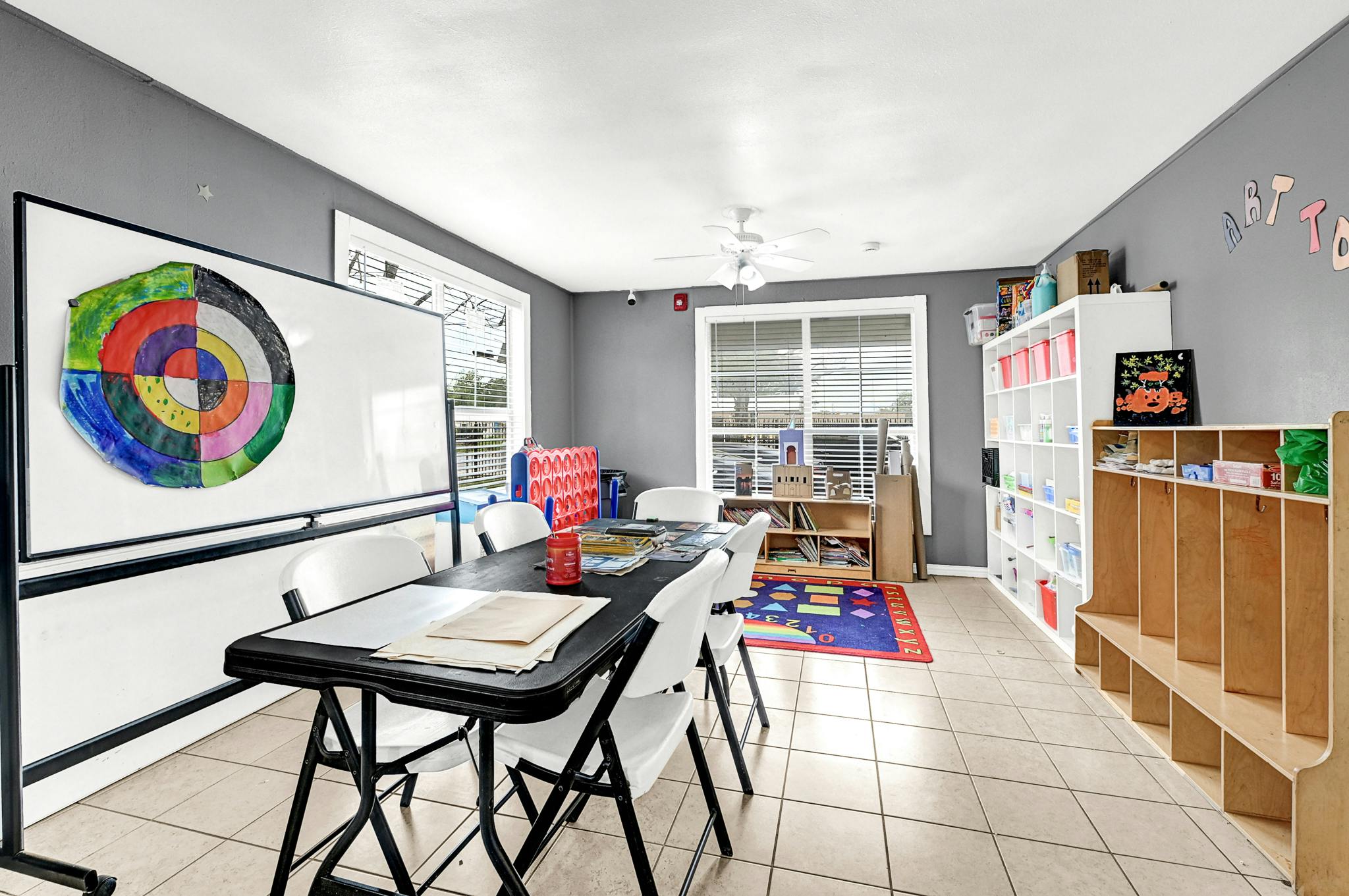 Classroom with a whiteboard, tables, chairs, and storage shelves