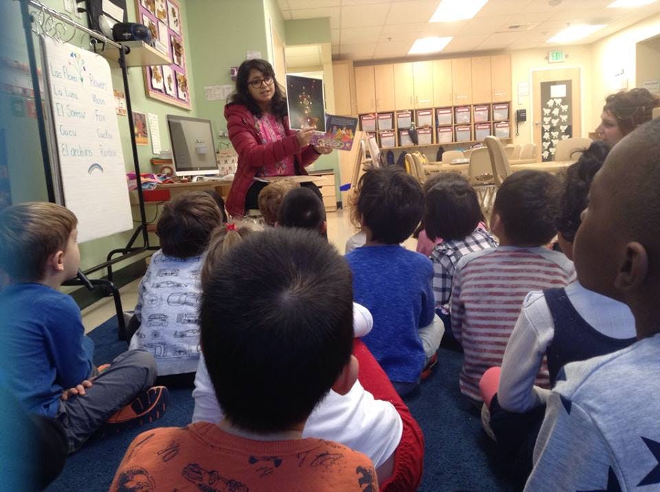 Person reading a book to a group of children in a classroom