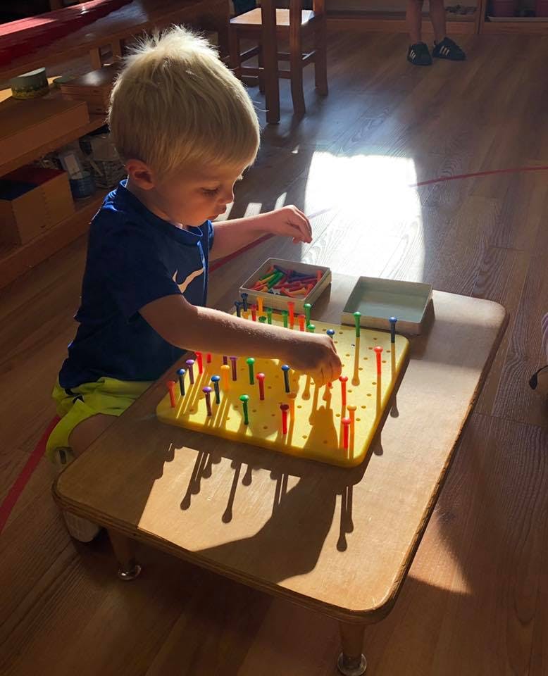 Child playing with a pegboard on a table