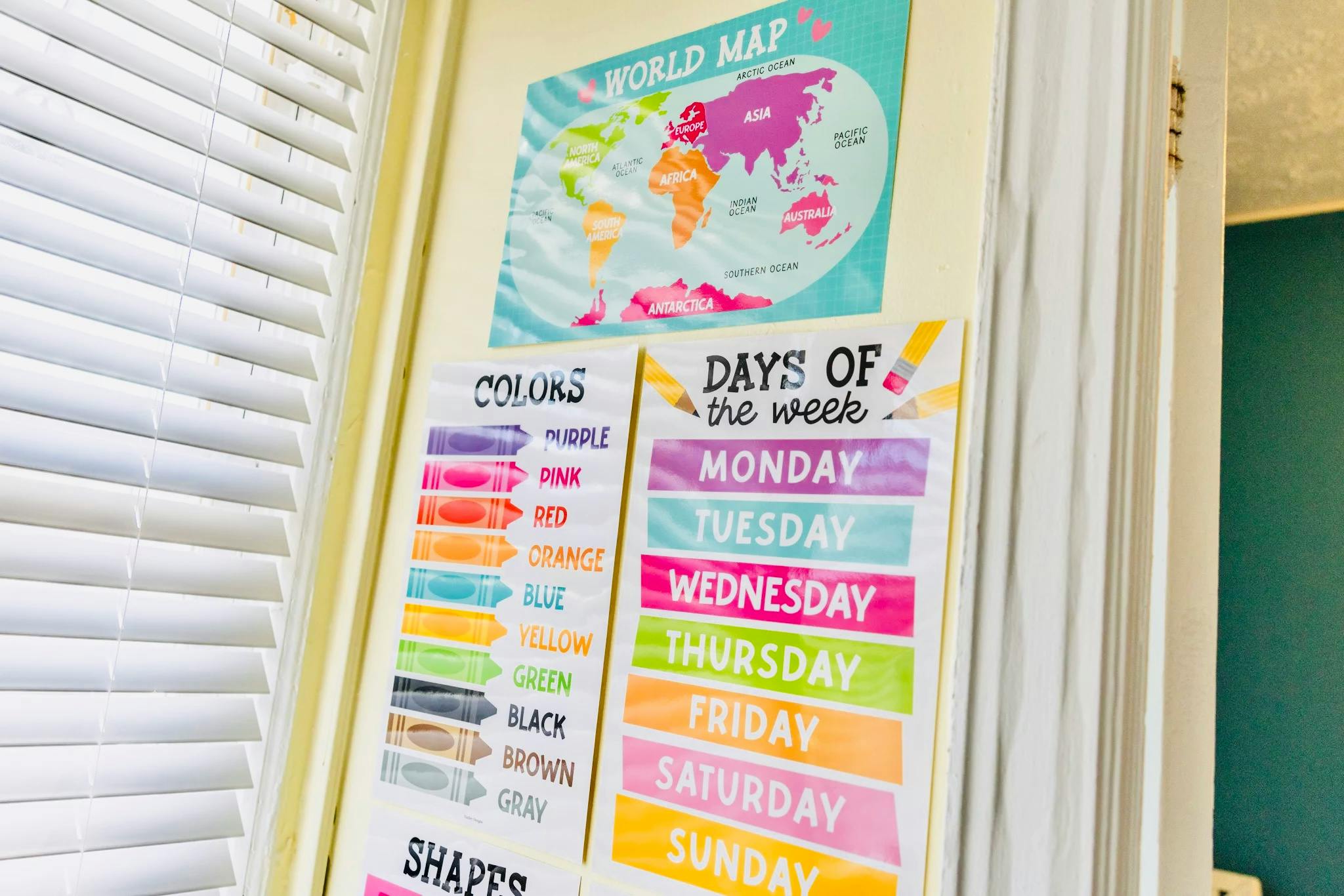 World map, colors chart, and days of the week chart on a wall