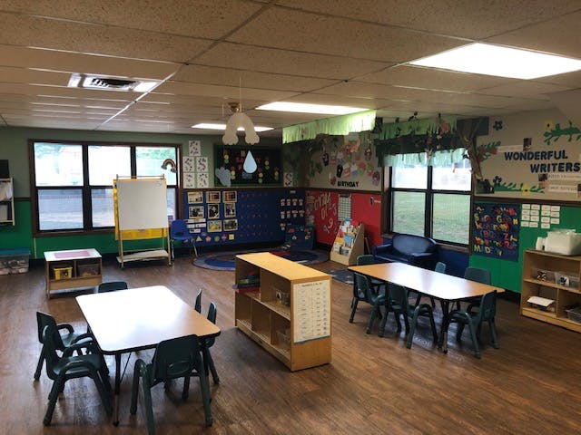 Empty classroom with small tables and chairs, and wall decorations