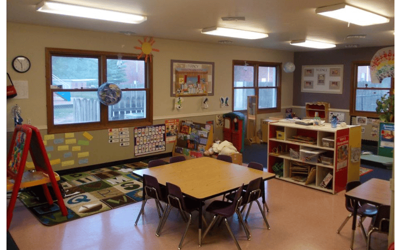A colorful classroom with small tables and chairs, and educational posters on the walls