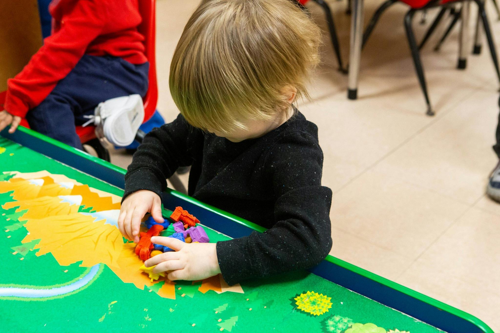 Child playing with colorful toys on a green table