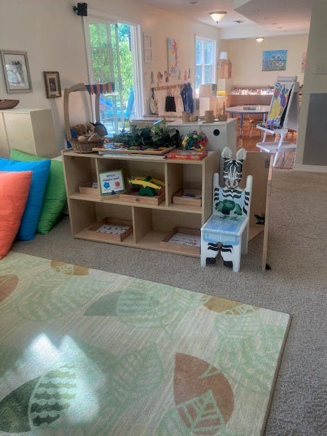 Child's classroom with wooden shelves, colorful pillows, and a zebra-themed chair