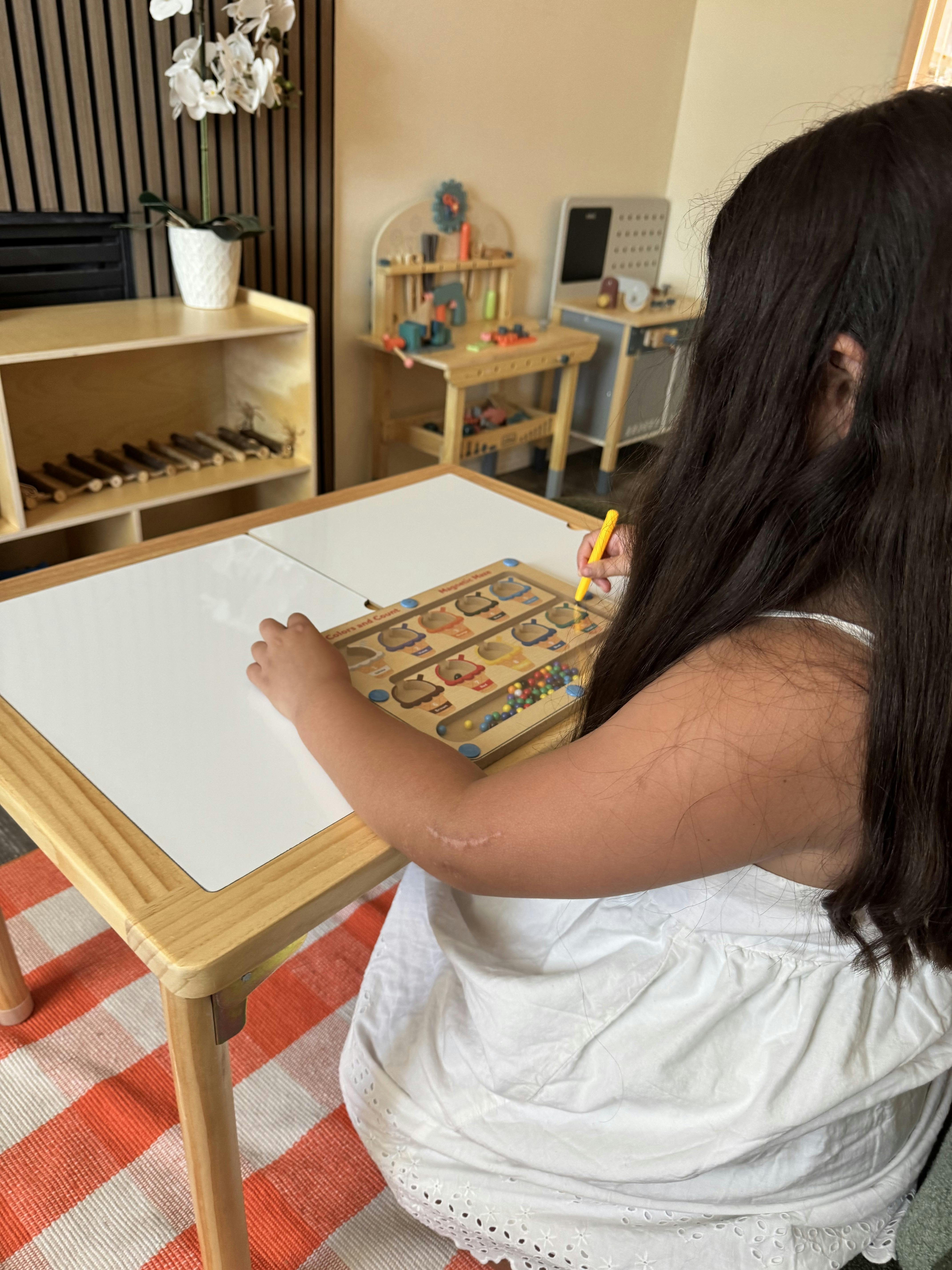 Child sitting at a wooden table playing with a magnetic color sorting toy