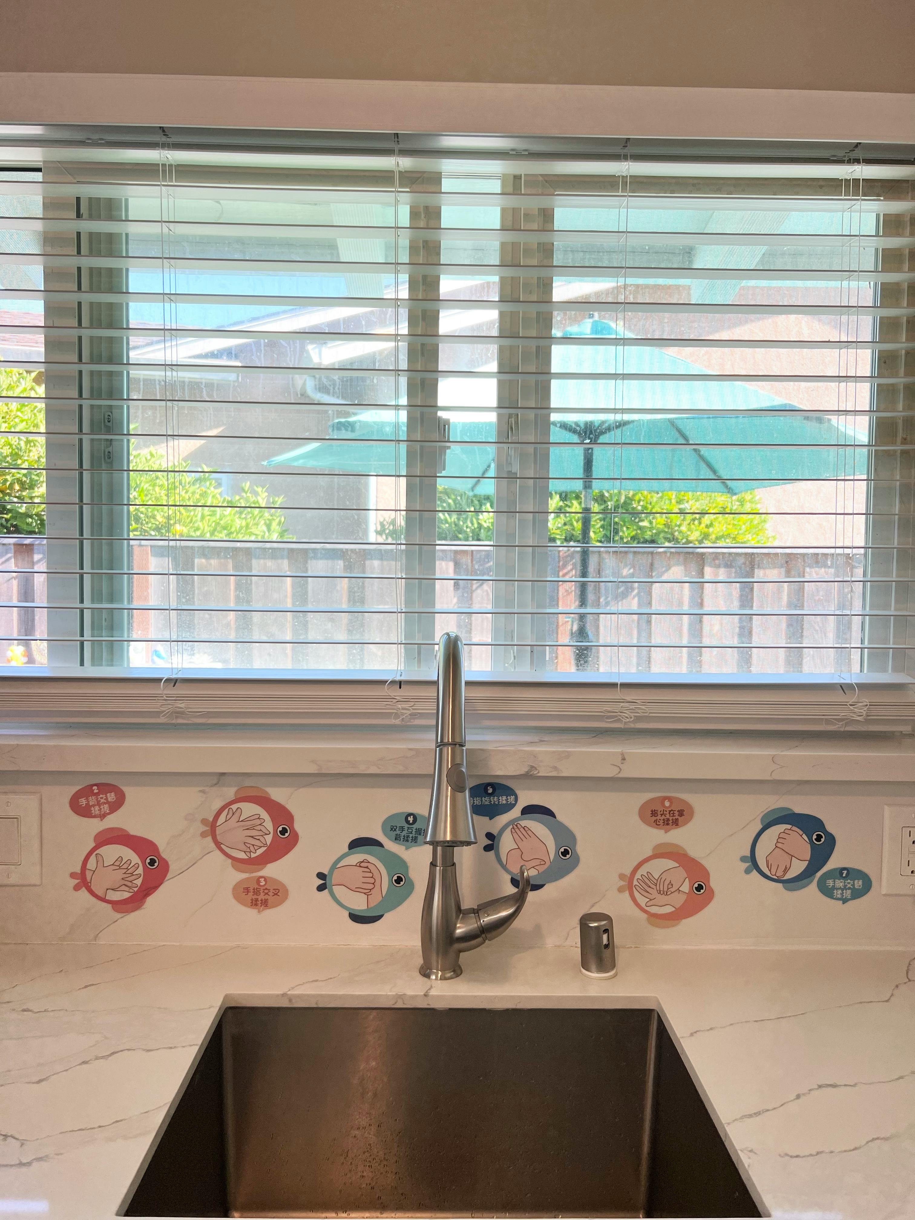 Kitchen sink with fish decals on the backsplash below a window
