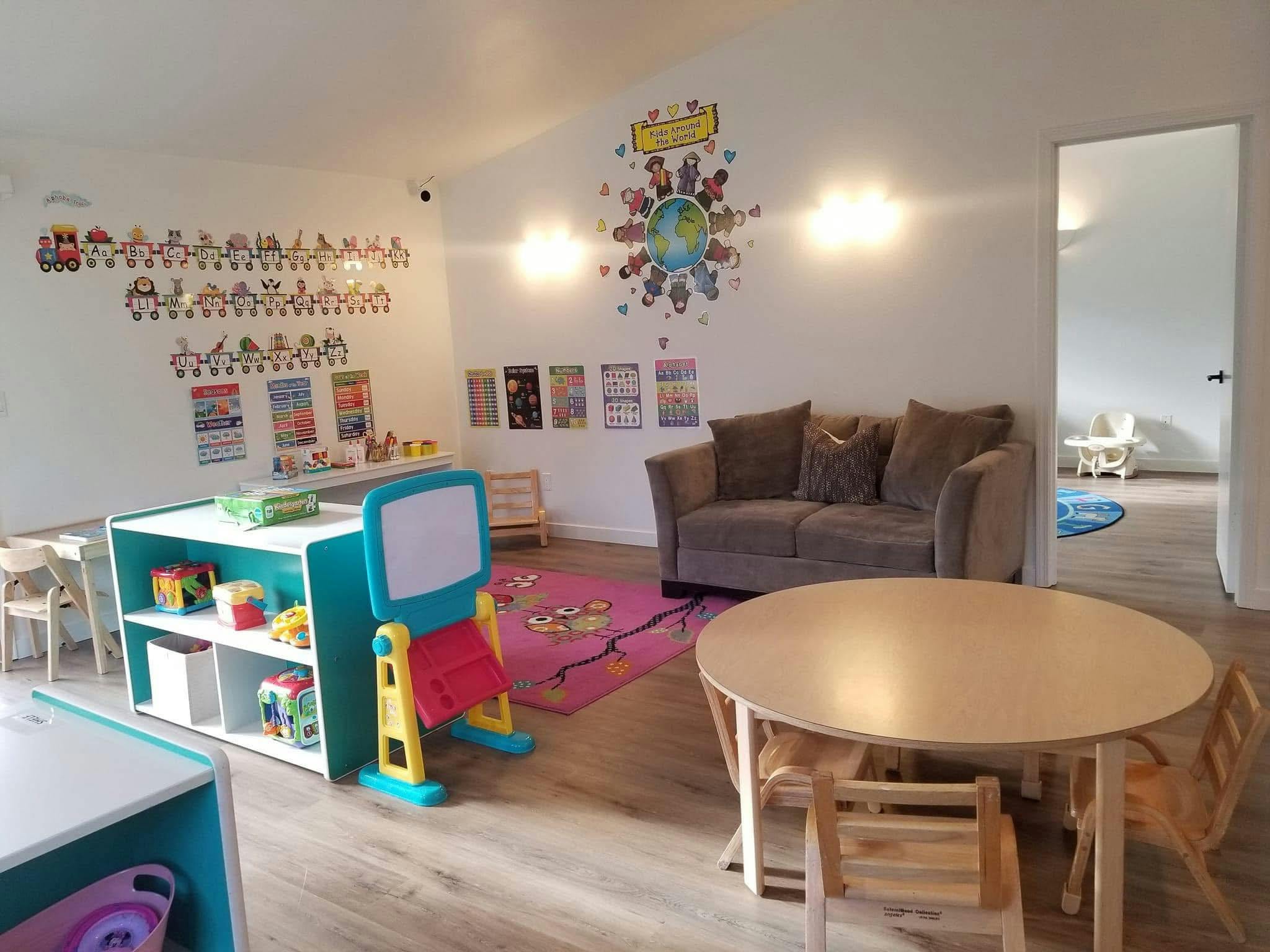 Classroom interior with small tables, chairs, toys, and educational wall art