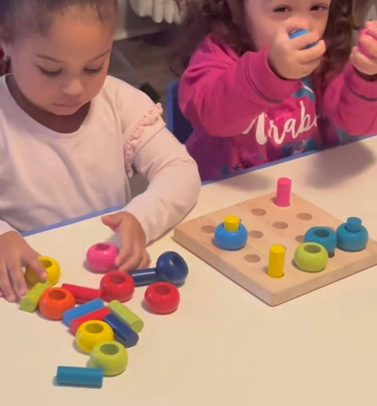 Two children playing with colorful wooden stacking toys at a table