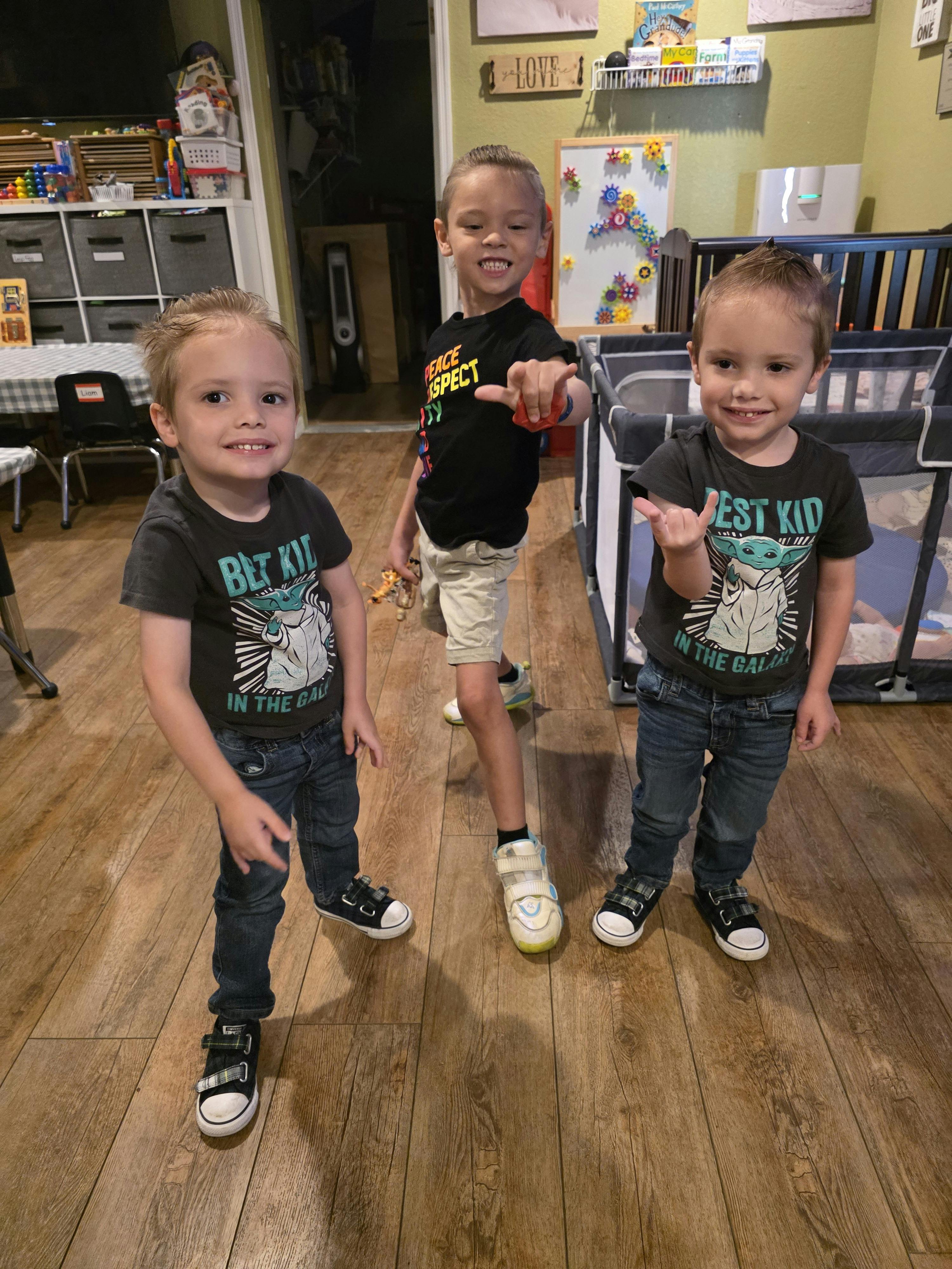Three children standing on a wooden floor