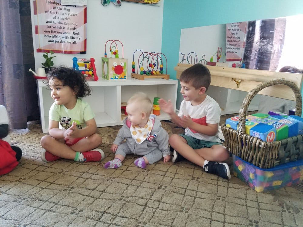 Three children sitting on the floor in a room with toys