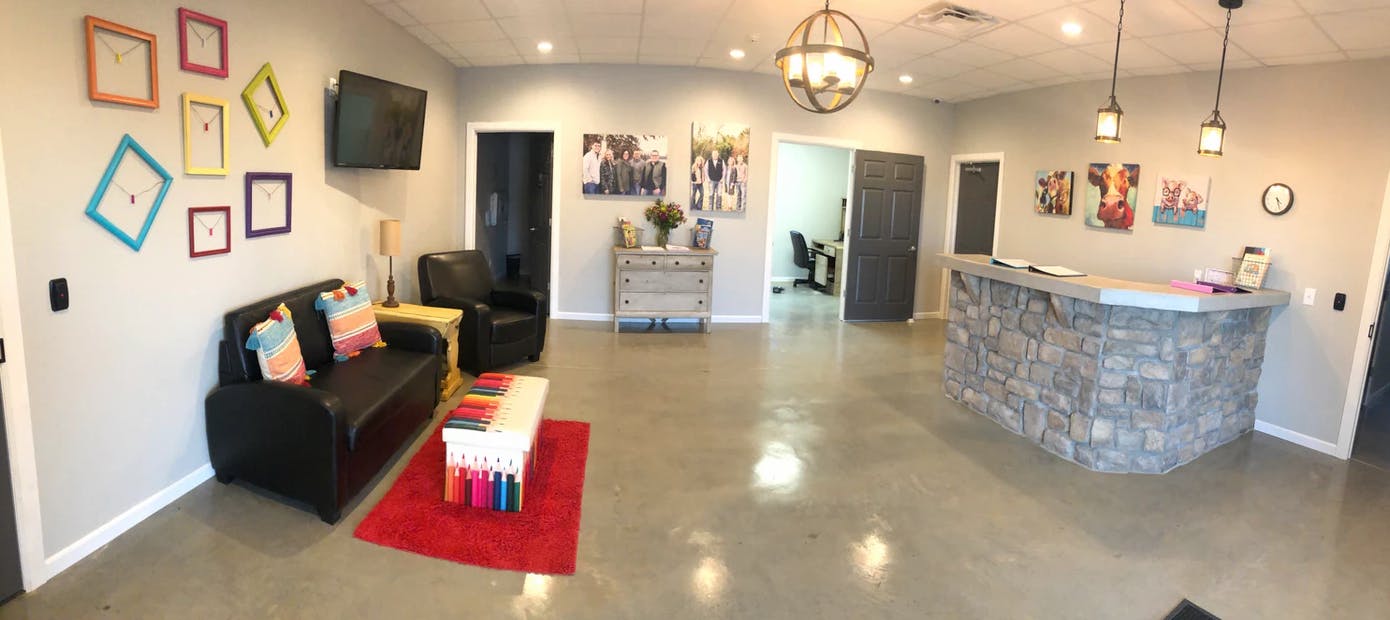 Waiting room with a stone reception desk, sofa, and framed art on walls