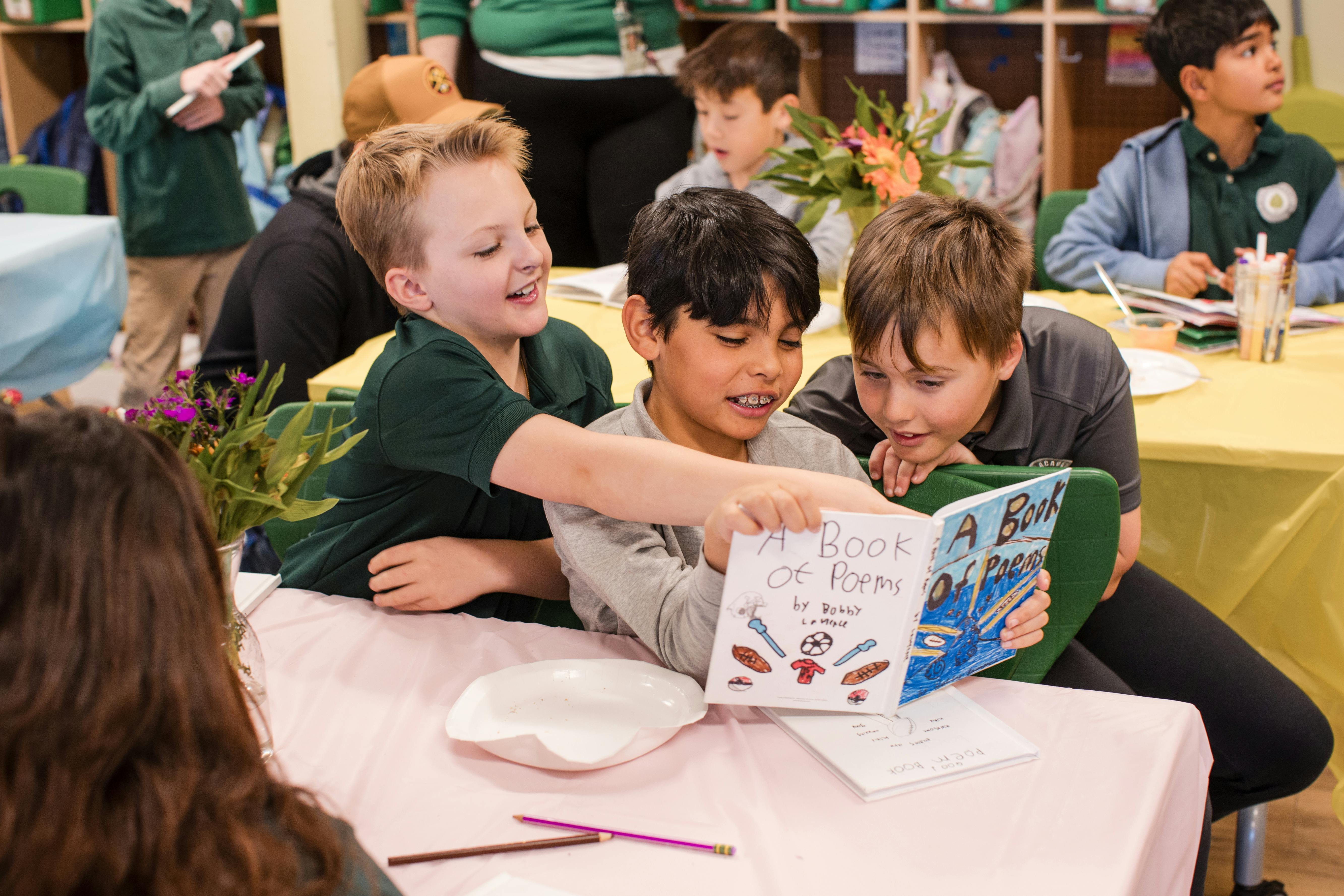 Three children looking at a book together at a table
