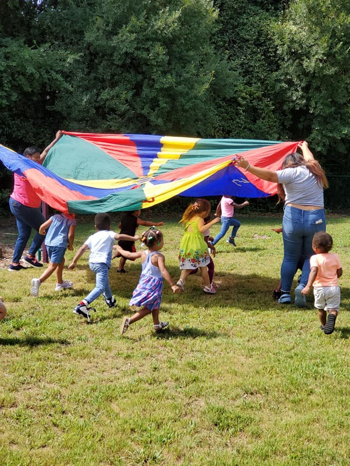 People and children playing with a colorful parachute outdoors
