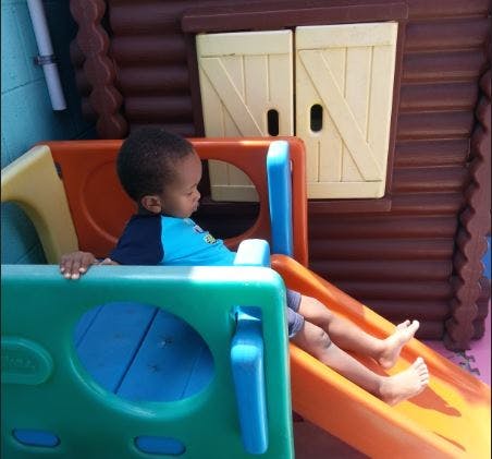 Child sitting on a colorful playground slide