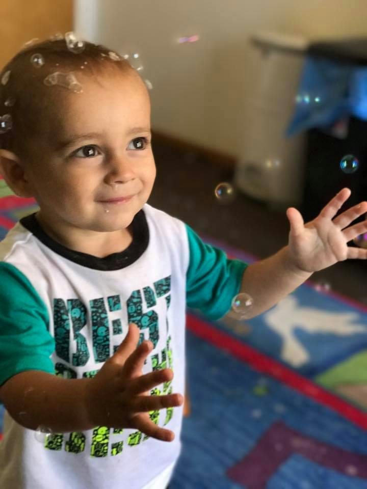 Child with bubbles on head and around hands