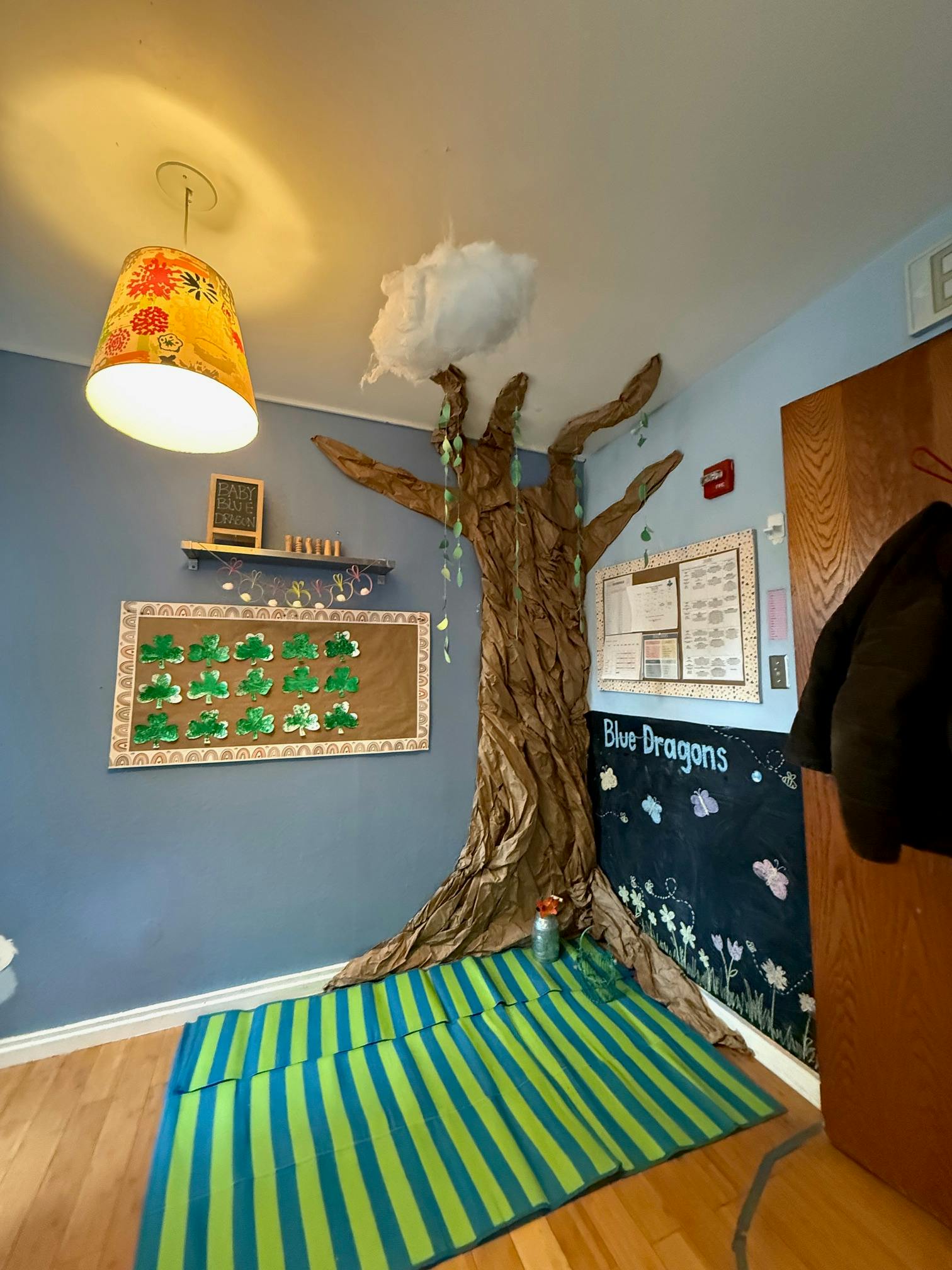 Classroom with a large tree decoration, blue walls, and a striped rug
