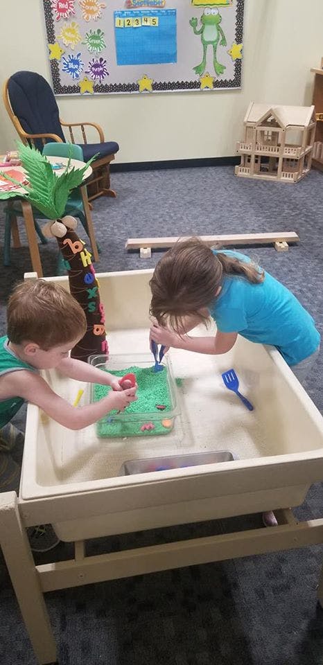 Two children playing with a sensory table in a classroom