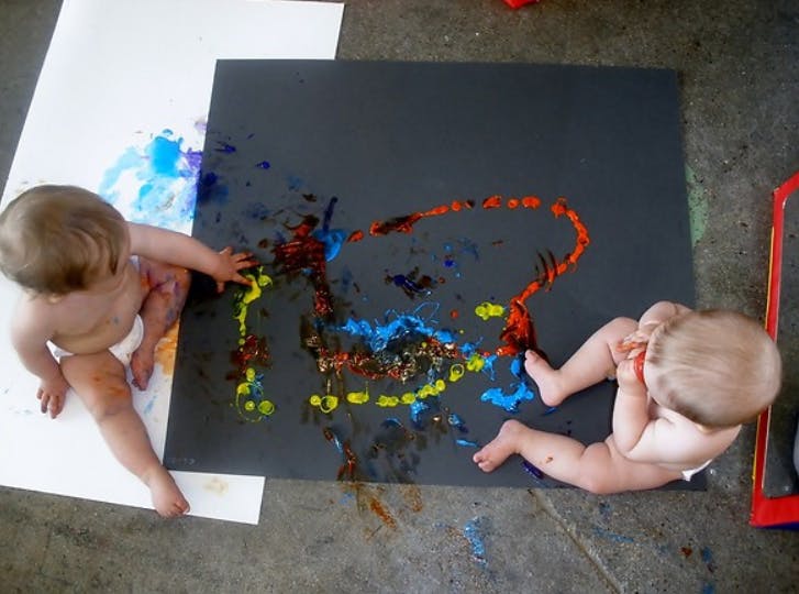 Two children playing with paint on large sheets of paper