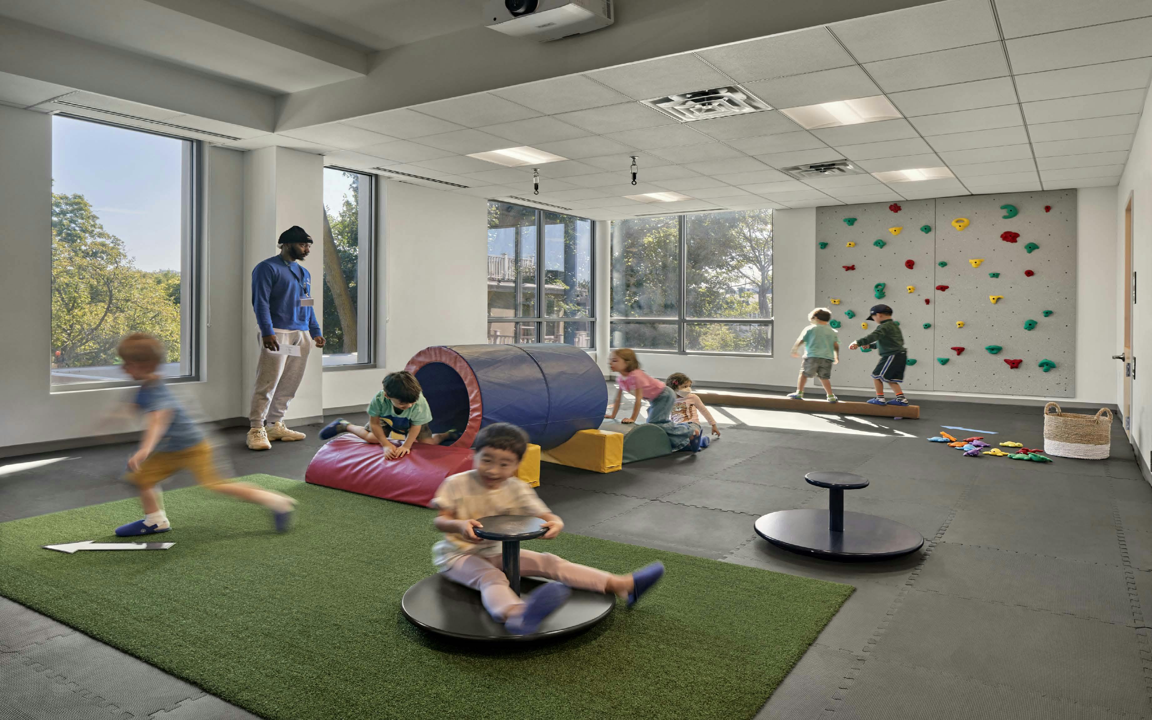 Adult supervising children playing in an indoor activity room