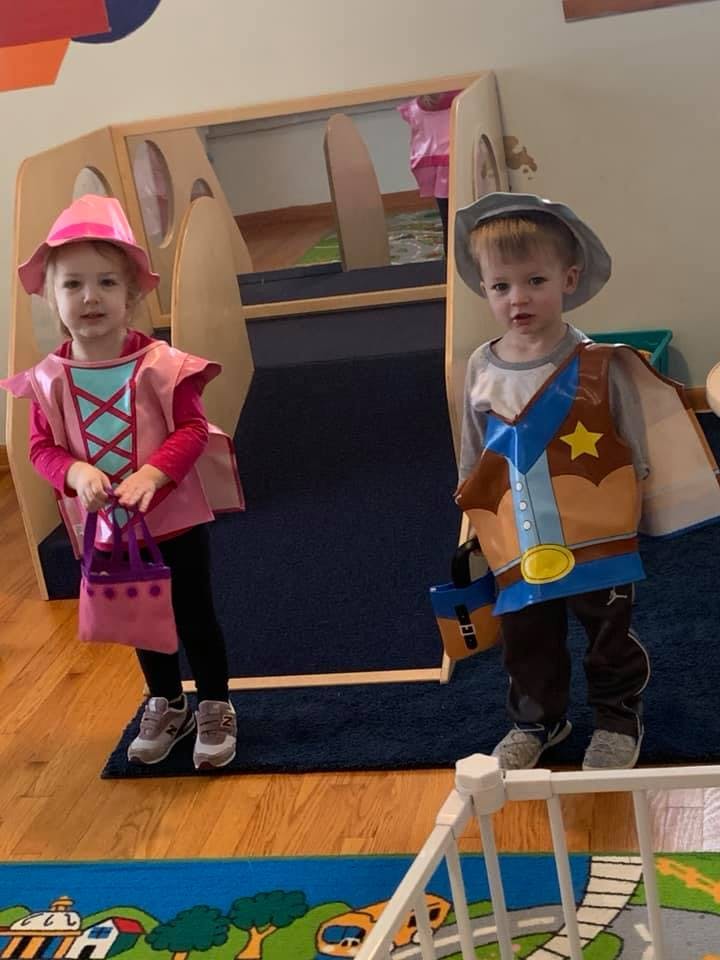 Two children in costumes, one dressed as a princess and one as a cowboy