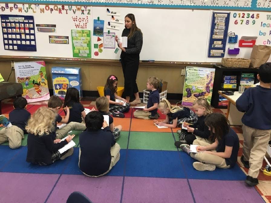 Adult teaching children sitting on a classroom floor