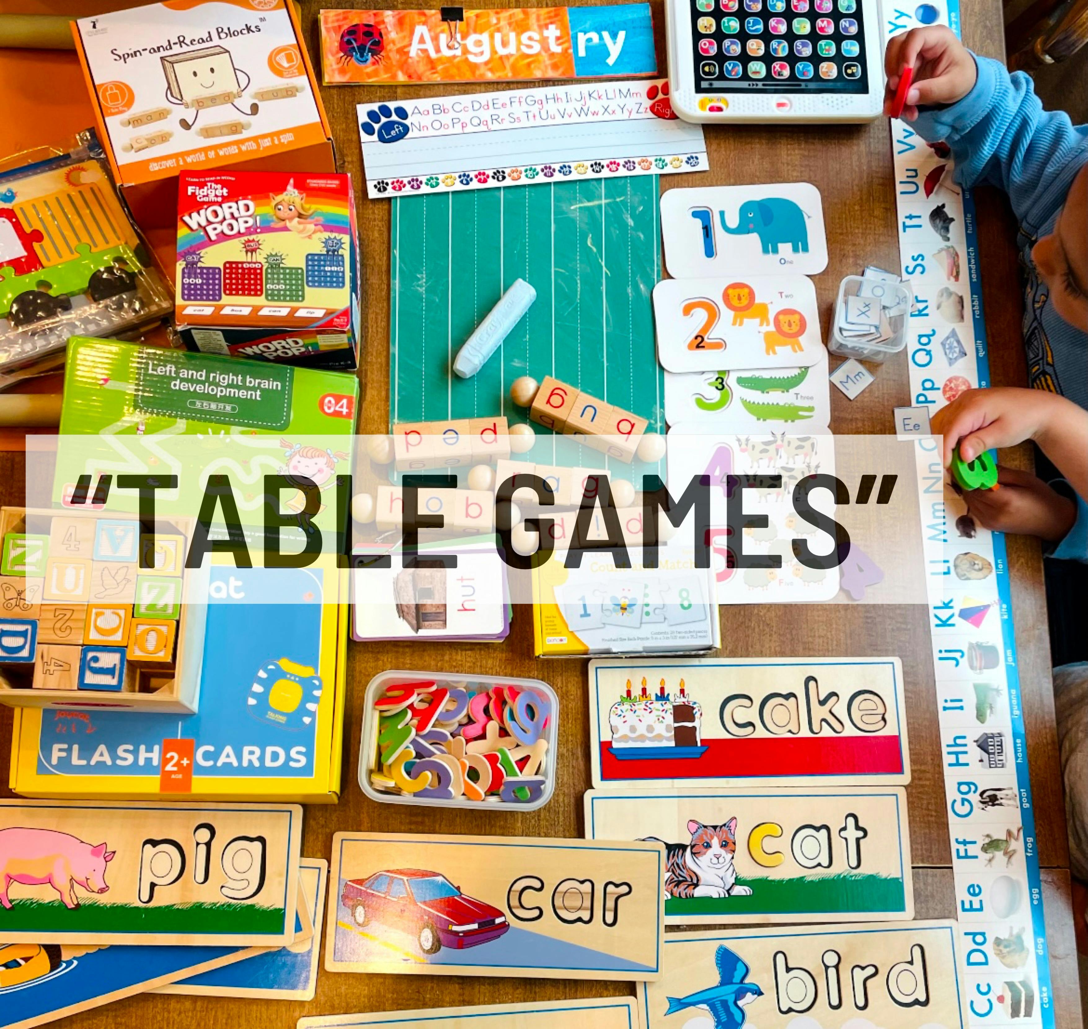 Child's hands playing with various learning games, blocks, and flashcards on a table