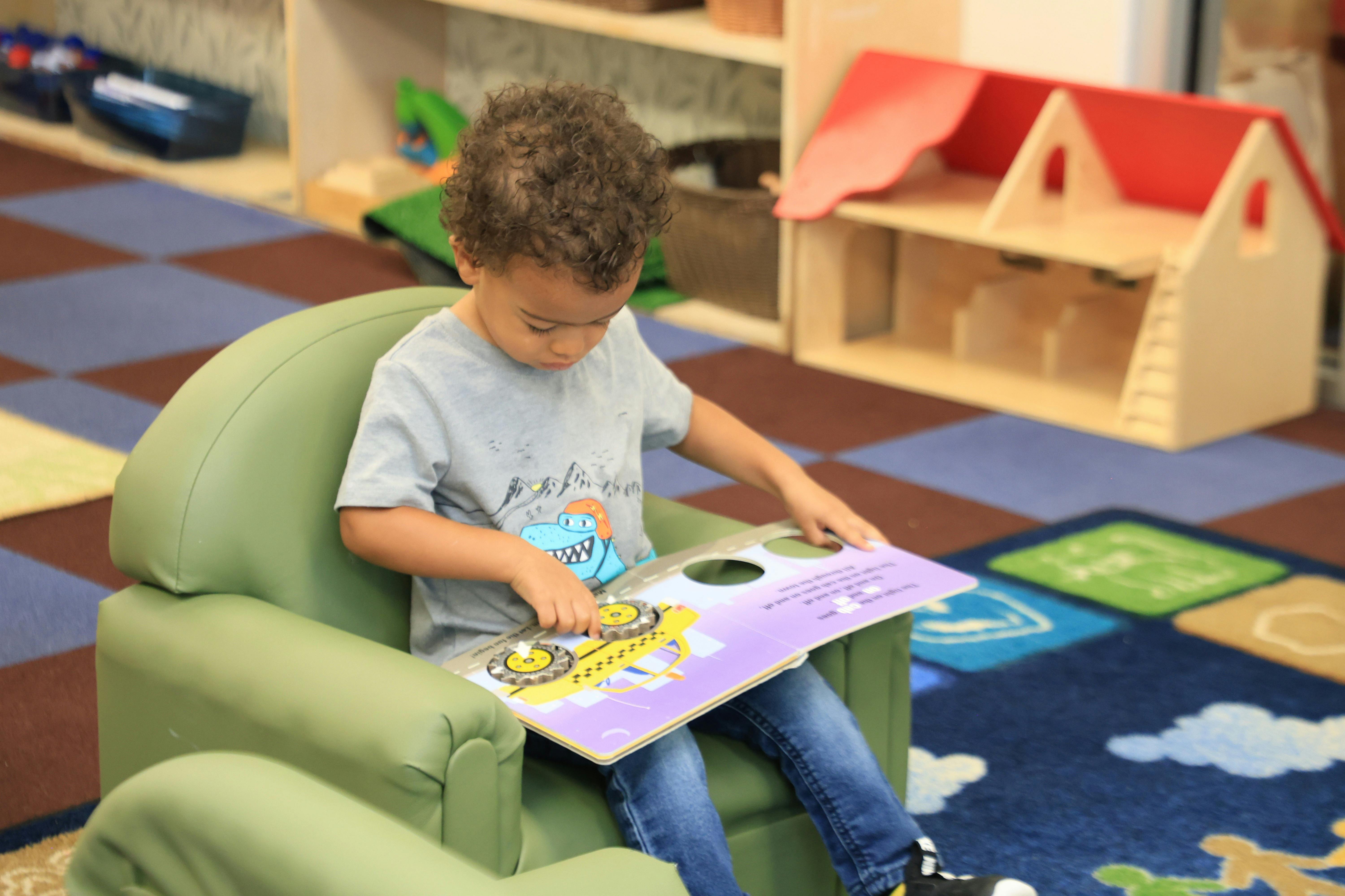 Child sitting in a chair and reading a book