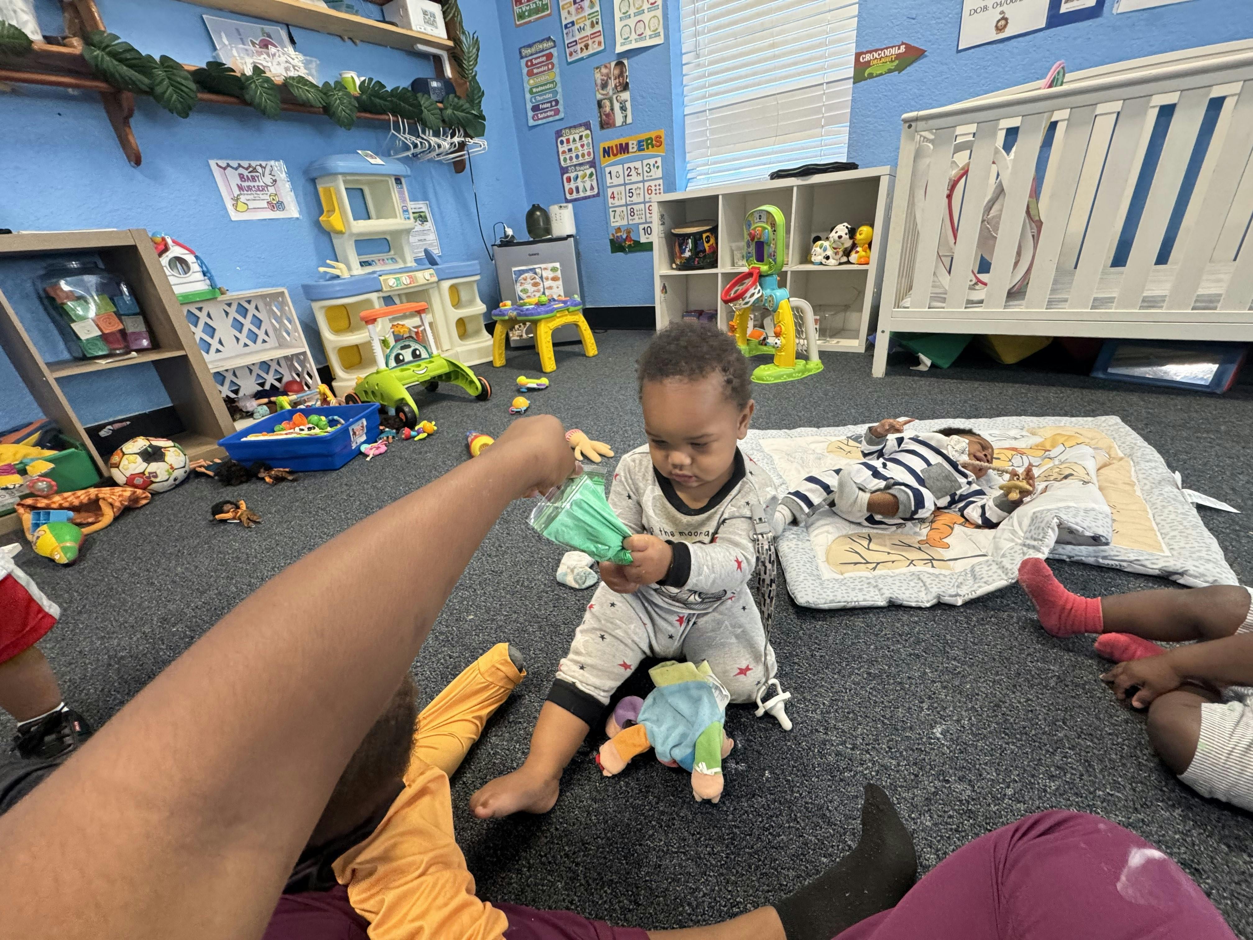 Child playing with a toy in a room with another person