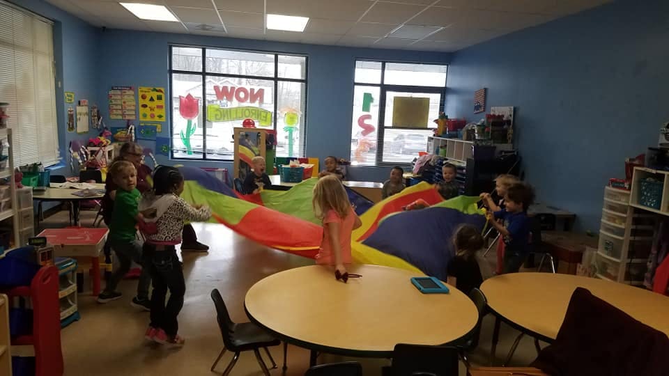 Children playing with a colorful parachute in a classroom