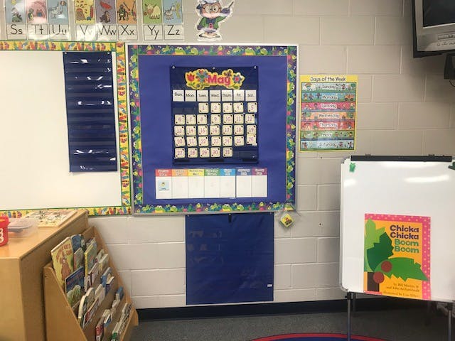 Classroom wall with a calendar displaying "May" and a whiteboard with a book