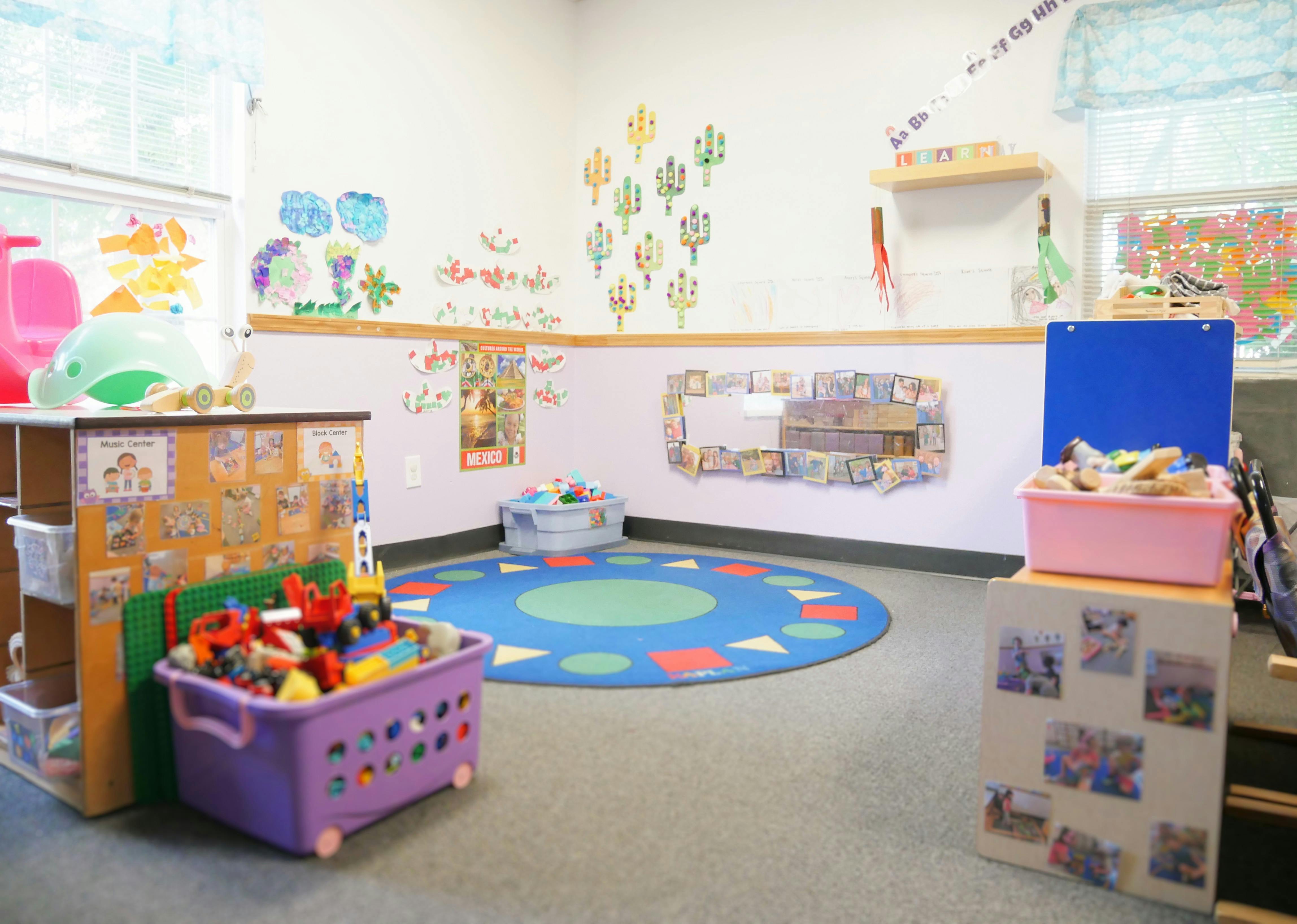 Playroom with a blue circular rug and toys in a purple bin full of toys