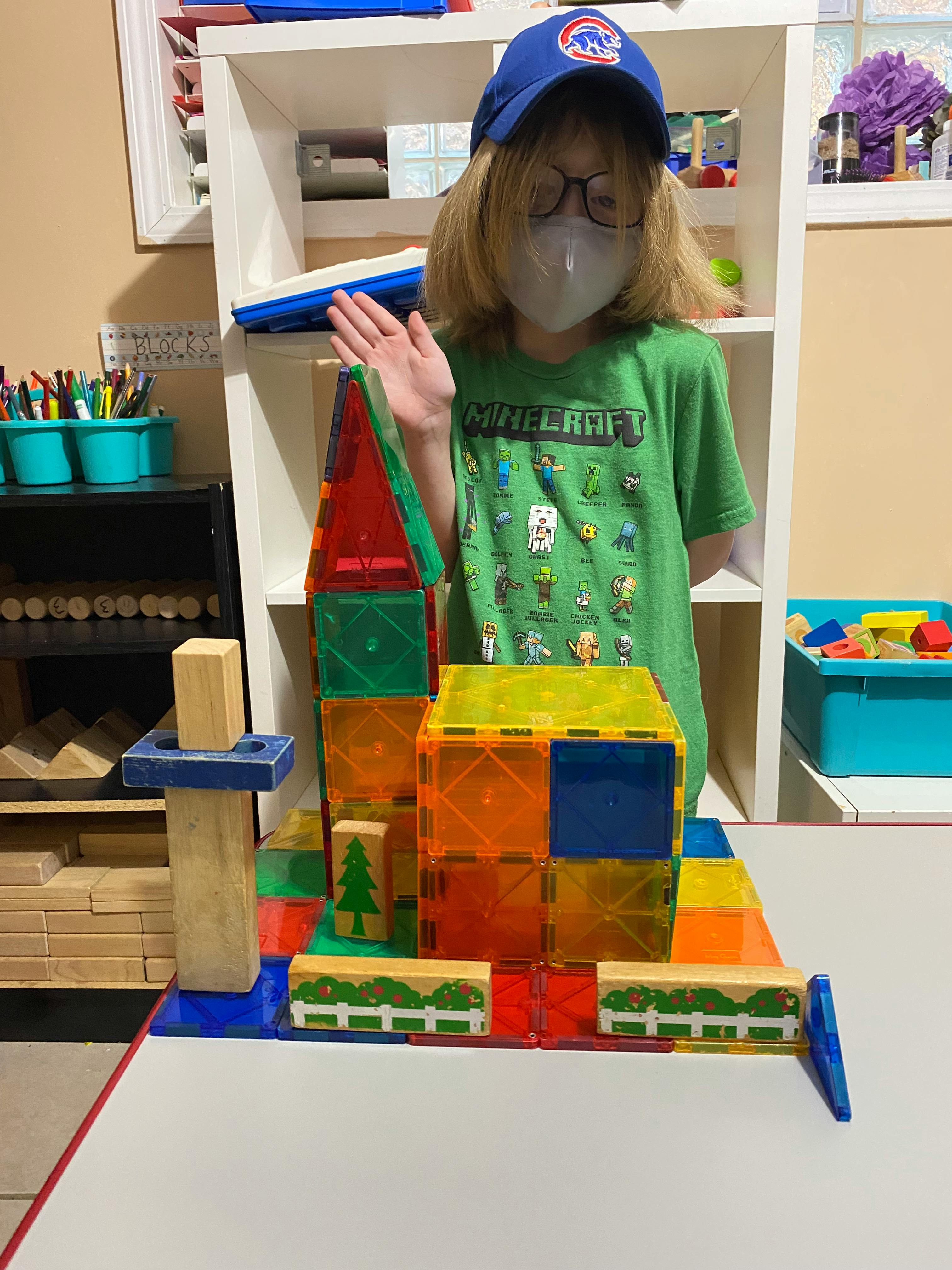 Child in a mask and hat standing behind a magnetic block structure