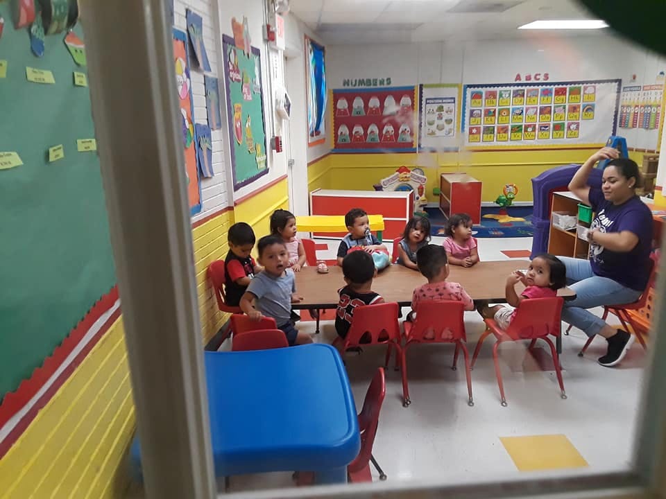 Adult and children sitting at tables in a classroom