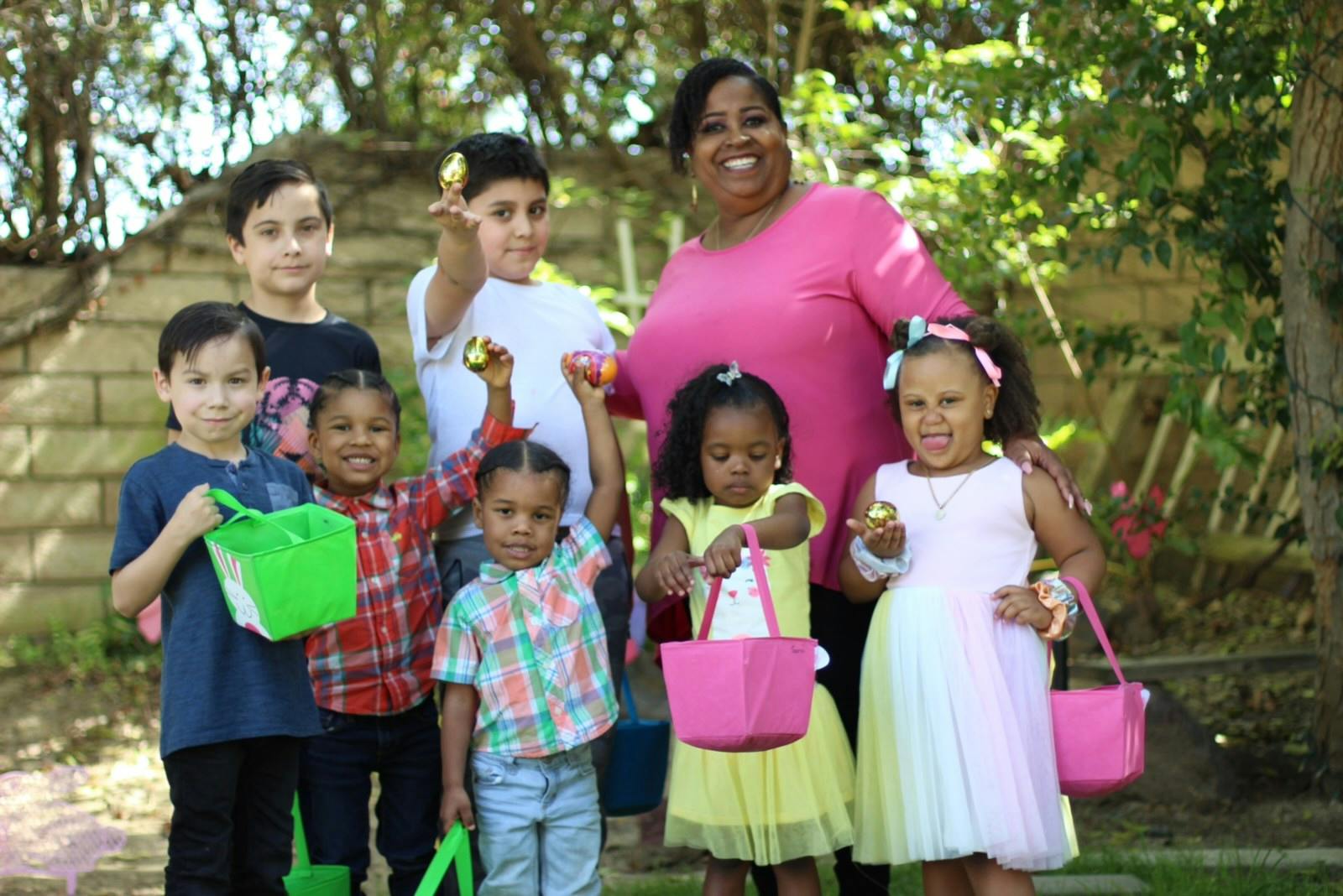 Adult and children holding baskets and plastic eggs outdoors