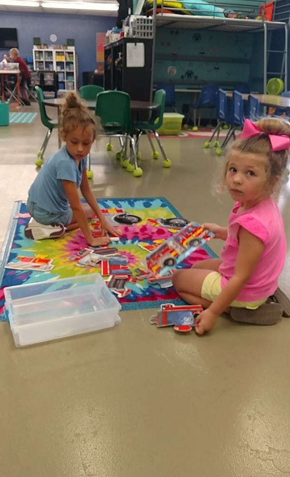 Two children playing with puzzles on a colorful rug
