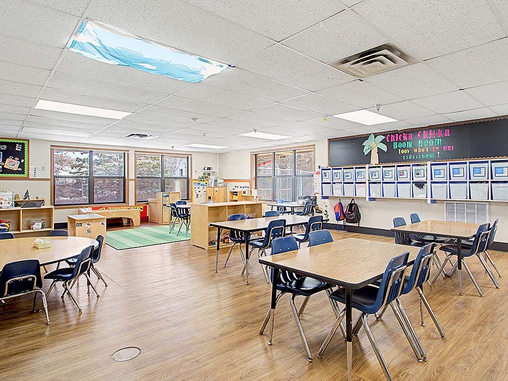 Empty classroom with tables, chairs, and windows