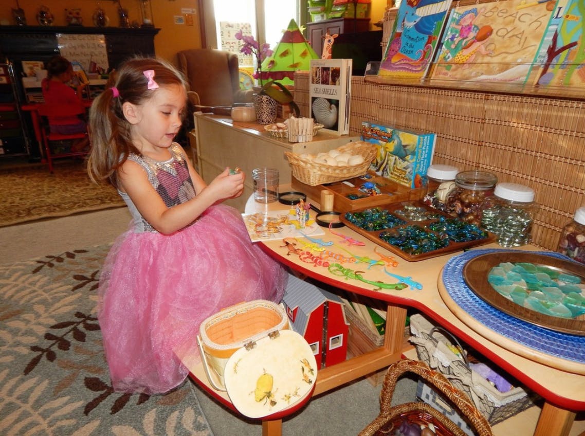 Child in a pink dress playing with items on a table