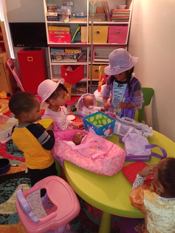 Children playing with dolls and toys around a table