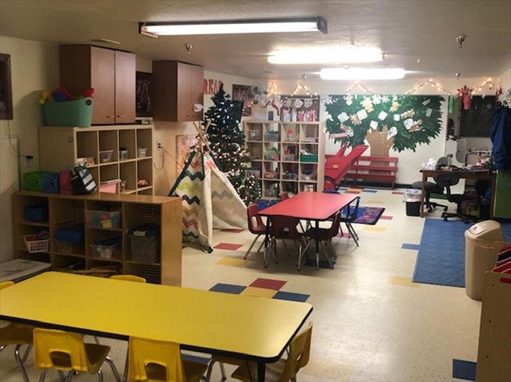 Classroom with tables, chairs, storage shelves, and a teepee